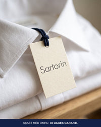Hængemærke med Sartorin på en foldet hvid skjorte